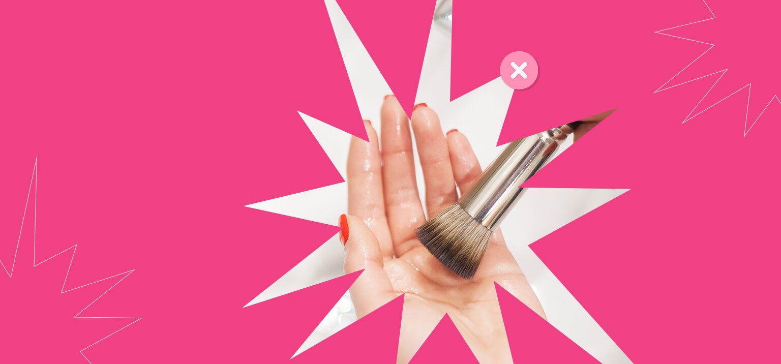 Pincel de maquiagem sobre a mão com fundo rosa