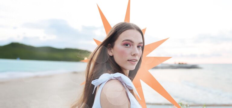 Modelo em praia com maquiagem vibrante e sol ao fundo