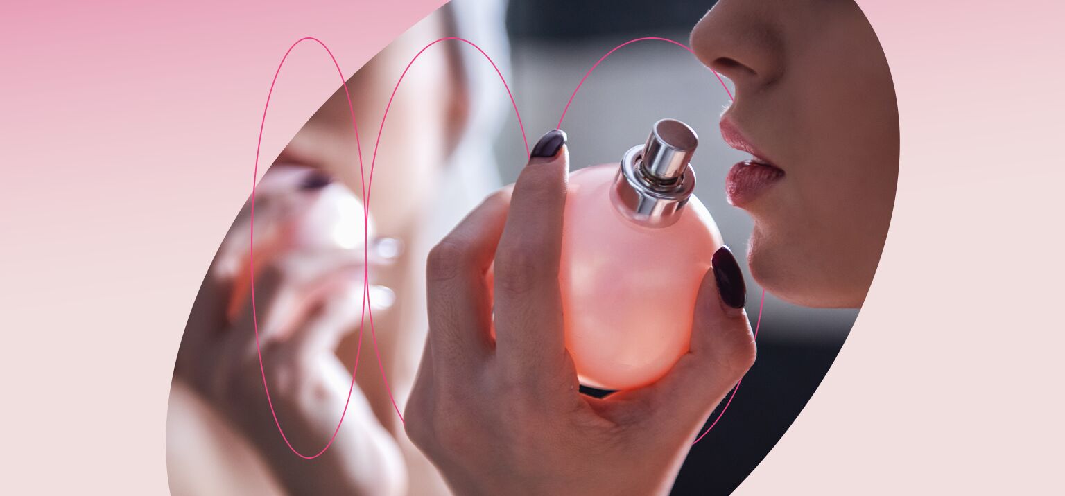 Mulher segurando frasco de perfume rosa