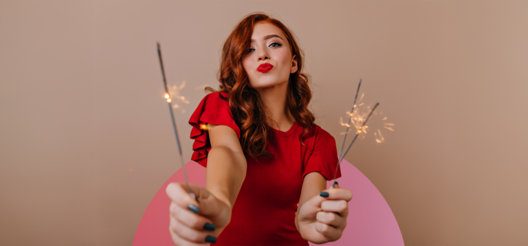 Mulher com roupa vermelha segurando fogos de artifício.