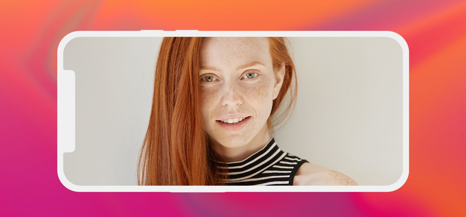 Mulher com cabelo ruivo e sardas, sorrindo para a câmera.