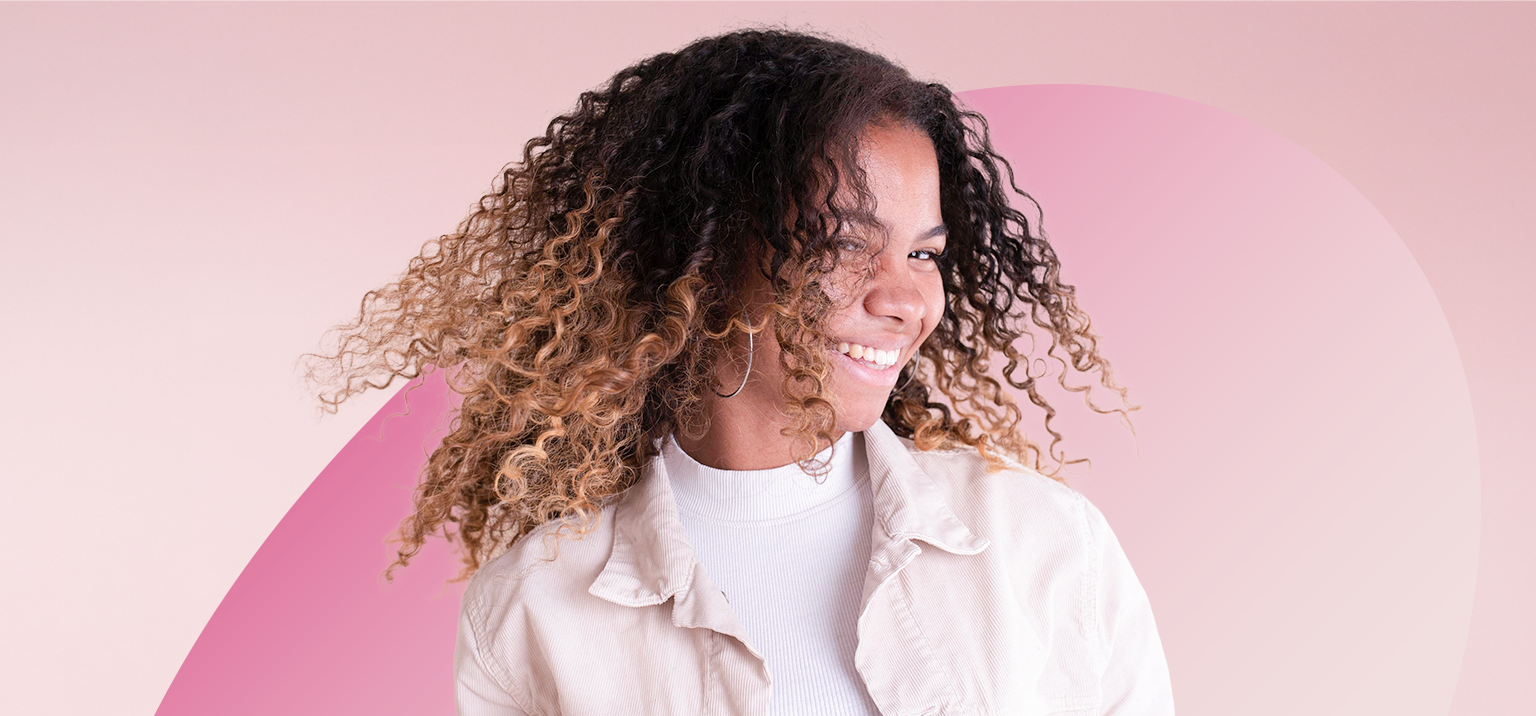 Mulher sorrindo com cabelo cacheado e longo