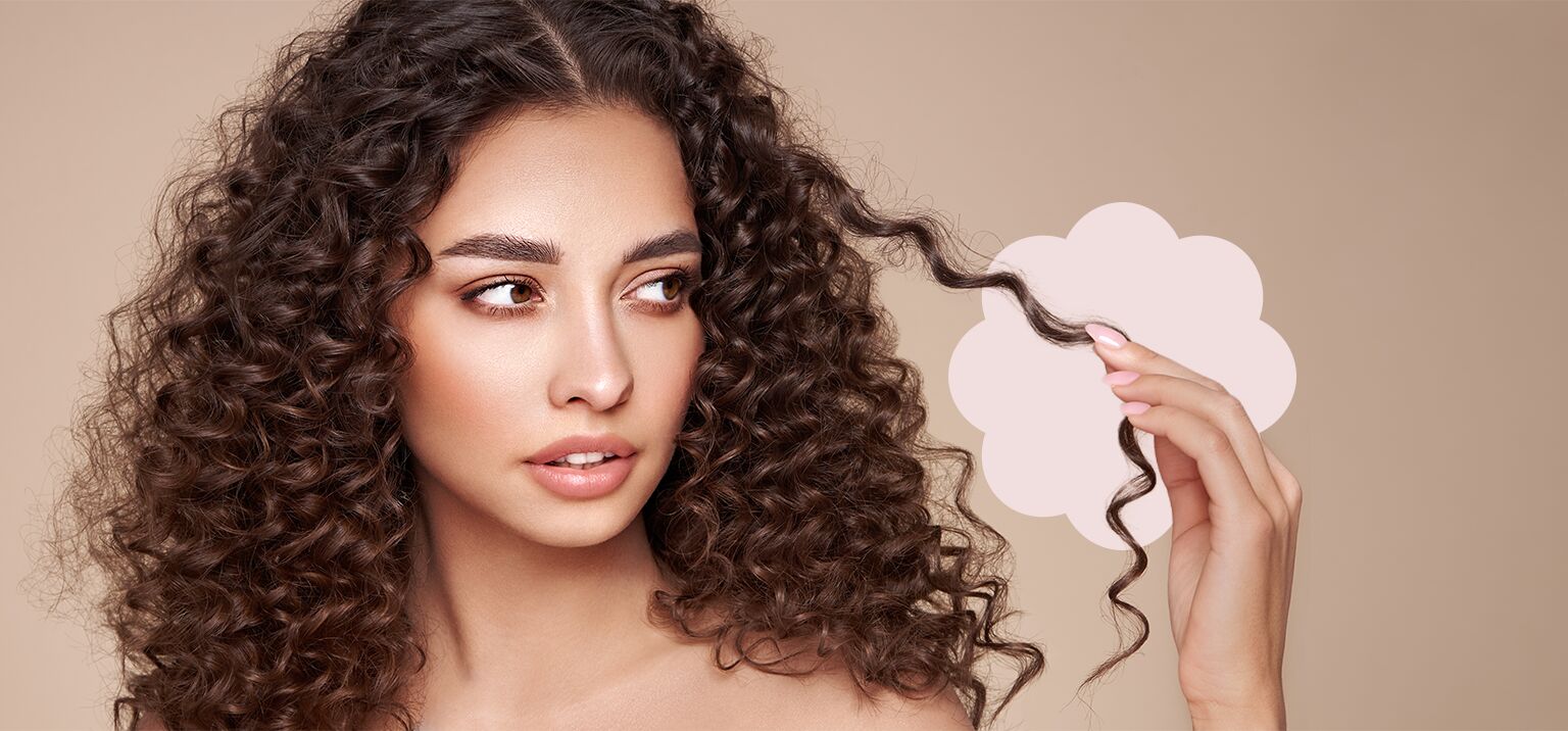 Modelo com cabelo cacheado segurando um fio de cabelo