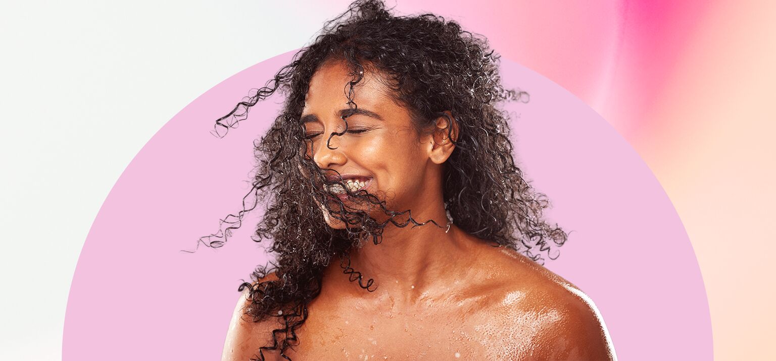 Mulher sorrindo com cabelo cacheado molhado