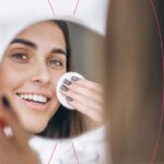 Mulher sorrindo enquanto se cuida no espelho