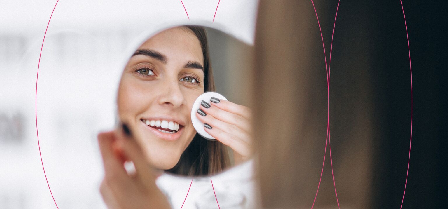 Mulher sorrindo enquanto se cuida no espelho