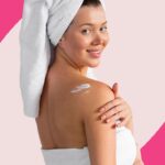 Mulher com toalha aplicando creme na pele