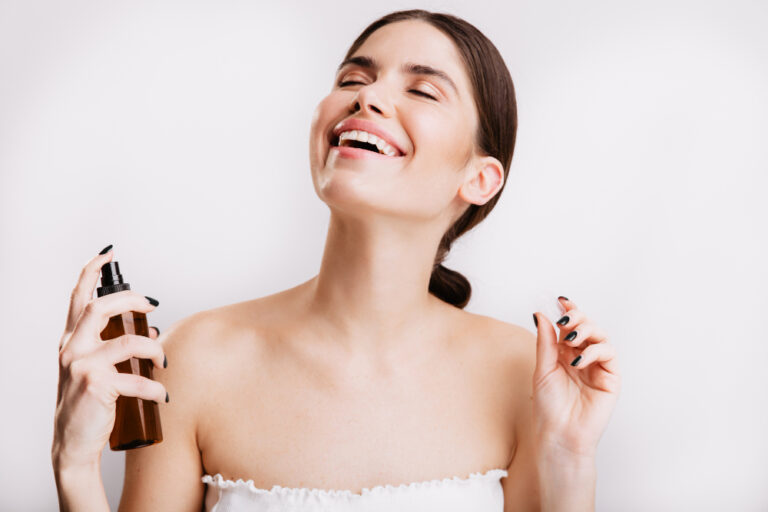 Mulher aplicando perfume no pescoço com um frasco em spray, representando o uso de perfumes importados em promoção para o dia a dia e ocasiões especiais.
